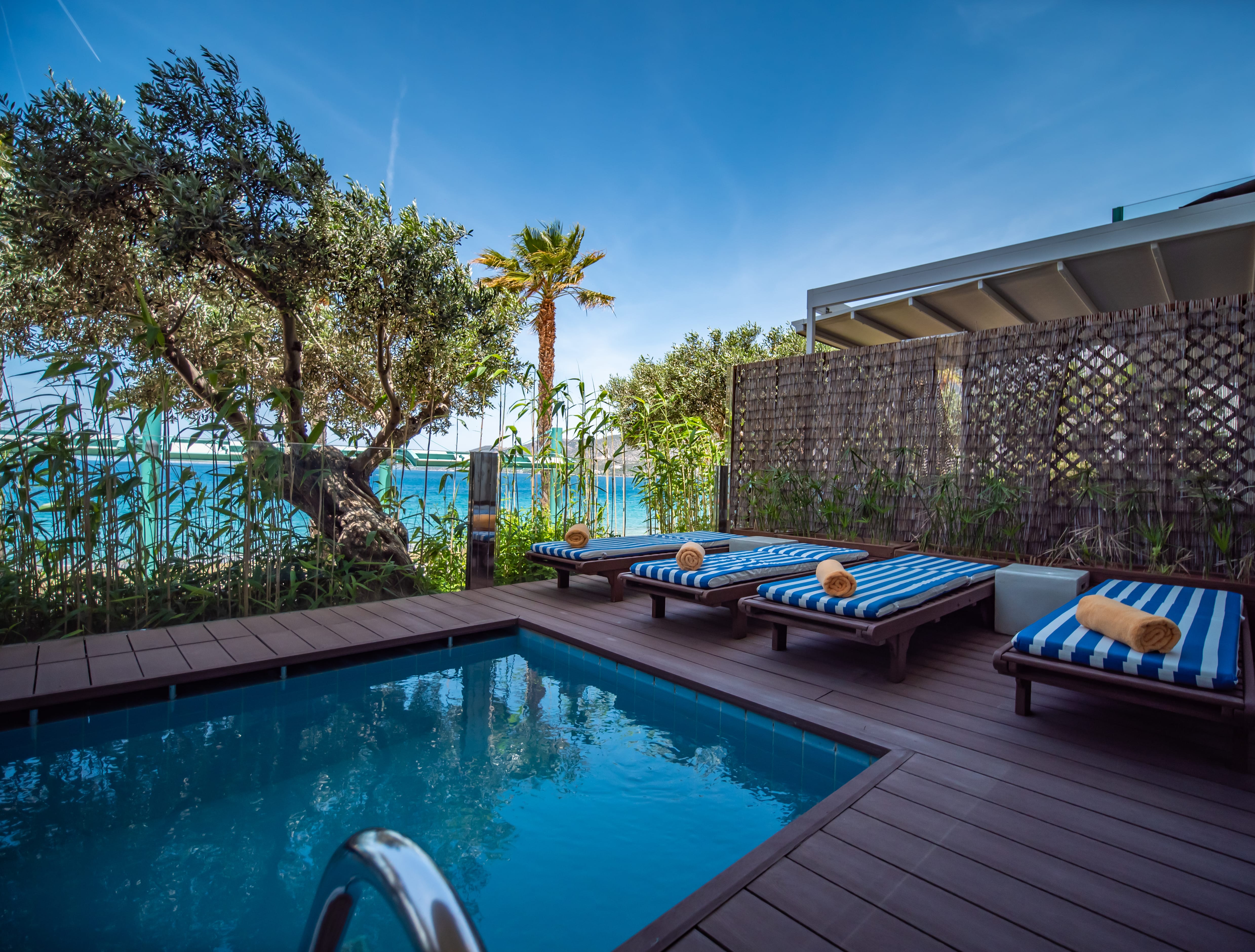 a pool with lounge chairs and a deck with a tree and a building